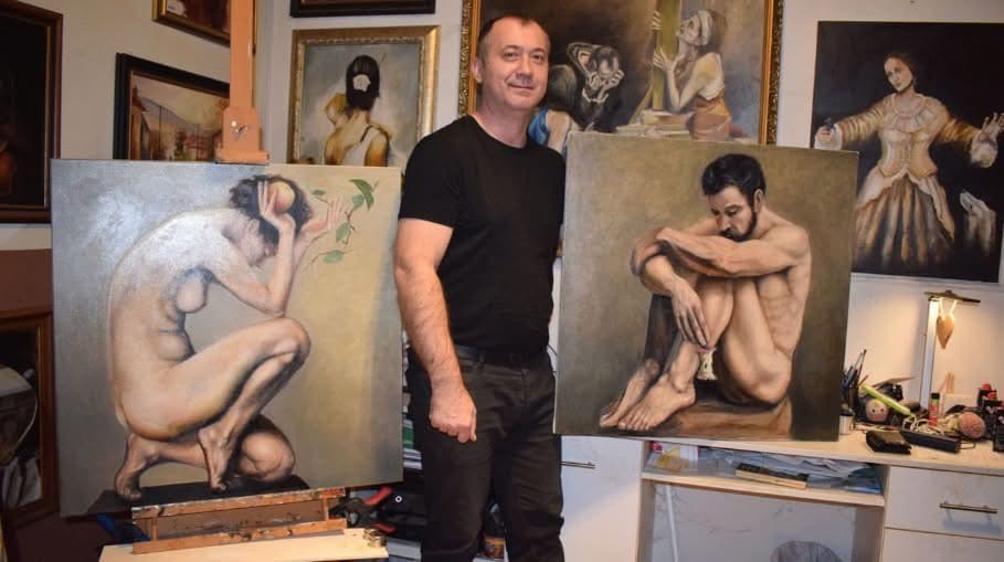 Nagy Krisztián két saját figurális festménye között a műteremben